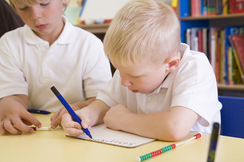 Two boys writing at a table Two boys writing at a table